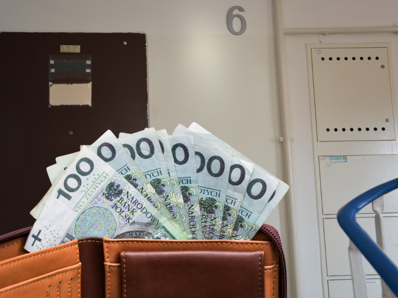 Portfel z banknotami i widok na klatkę schodową mieszkania
