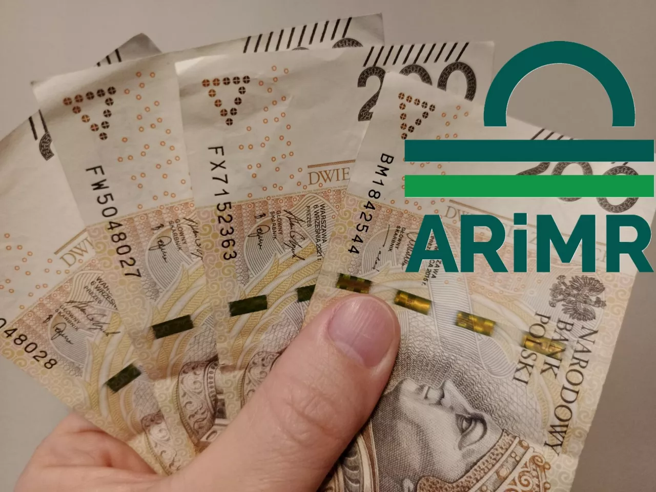 banknoty w dłoni, logo ARiMR